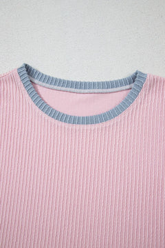 Close-up of a pink ribbed sweater with a blue neckline on a light gray background