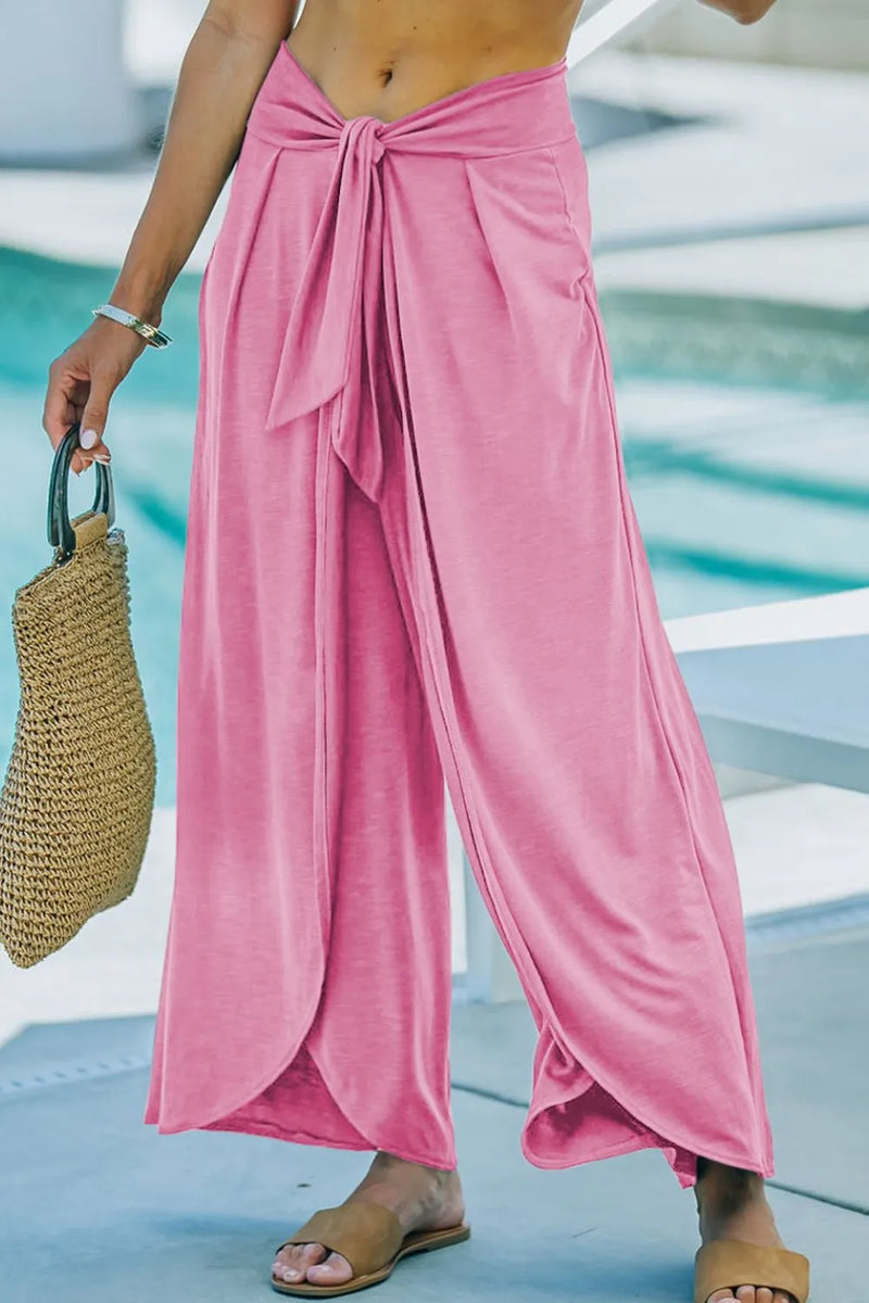 pink wide-leg pants with a sarong vibe to them as they are tied below the belly button with a knotted sash tie