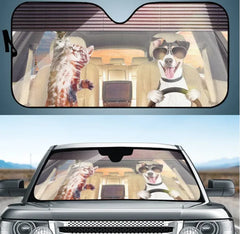 Car sunshade with a design of a cat and dog driving a car, placed on a car's windshield.