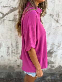 Person wearing a bright pink shirt against a textured wall.