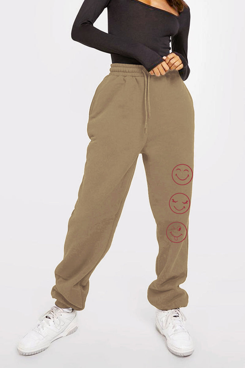 brown sweat pants with smiley face emojis down one leg