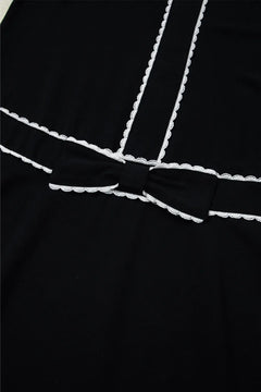 Black dress with white trim on a black background
