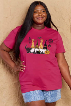 Pink t-shirt with Halloween-themed graphics. Four gnomes sitting behind a caldron with green brew bubbling out, a black cat with arched back on the right and a grinning jack o'lantern on the left with black 'sheet' ghosts, a bat and two black jack o' lantern silhouttes hovering above. Each gnome has a long pointy hat in either orange, black, or a combination of the two. The gnome on the left has a witch hat.