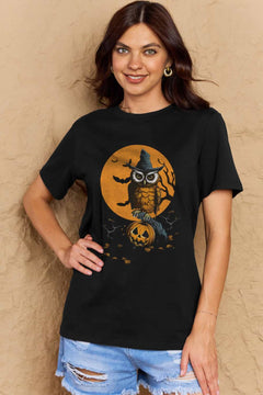 Woman wearing a black t-shirt with a Halloween-themed owl design against a beige background
