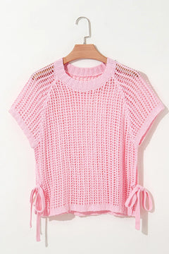 Pink crochet beach cover up top on a hanger against a white background