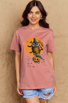 Woman wearing a pink t-shirt with a Halloween-themed owl design against a beige background