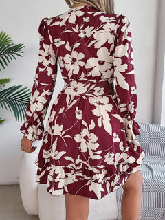 Woman wearing a burgundy and white floral dress with long sleeves in an indoor setting.