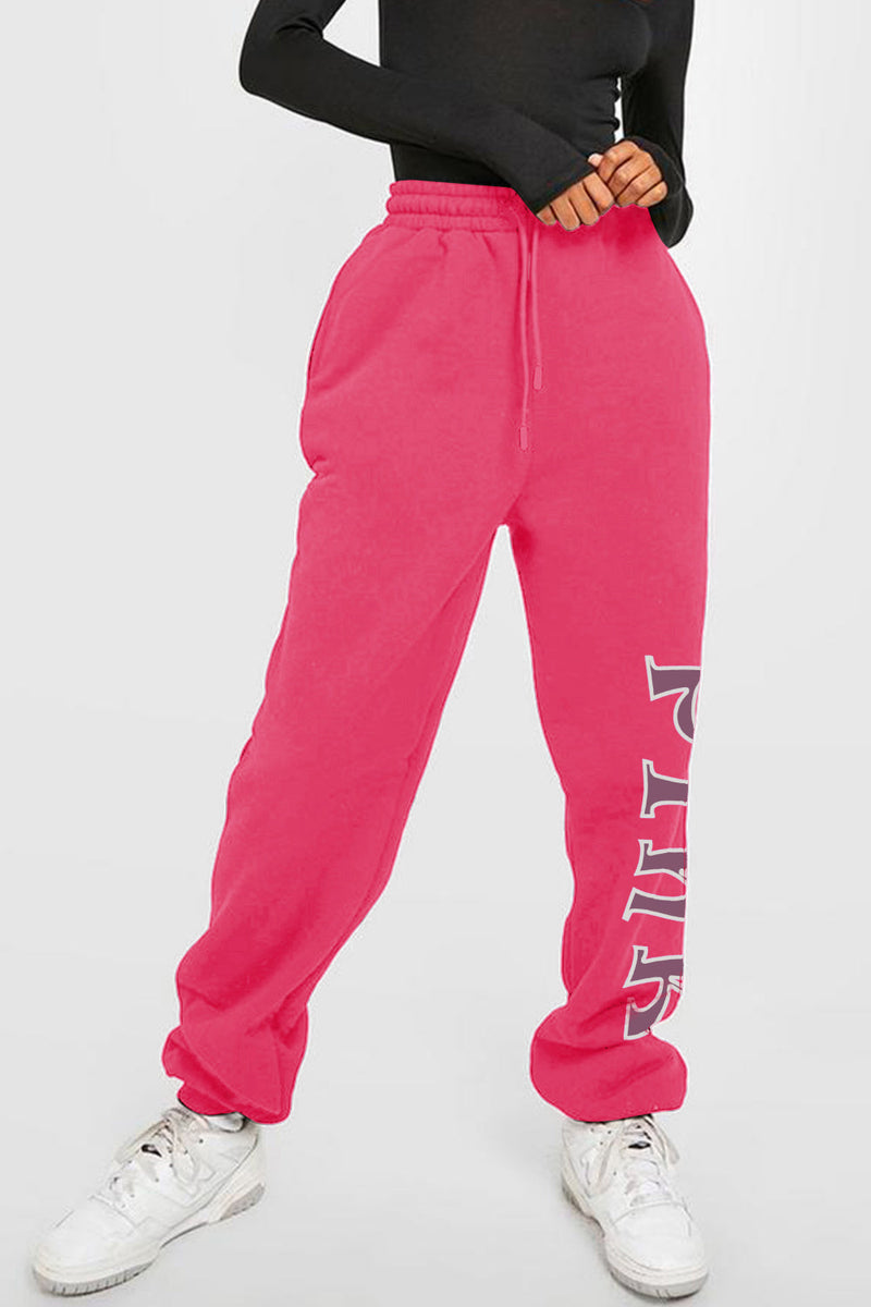 Pink drawstring sweat pants with pockets and the word PINK going down the left leg from knee to ankle in brownish letters outlined in white.