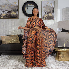 Woman in a tiger-striped 2 piece african style outfit standing in a stylish living room.