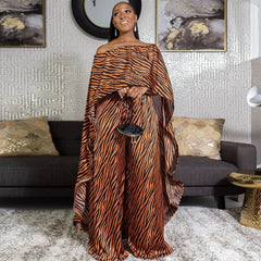 Woman in a tiger-striped 2 piece african style outfit standing in a stylish living room.