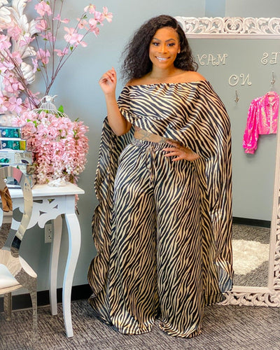 Woman wearing a zebra print 2 piece African style outfit standing in a room with decorative elements.