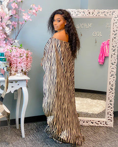 Woman in a zebra print 2 piece african style suit standing in front of a decorative mirror with floral decorations.
