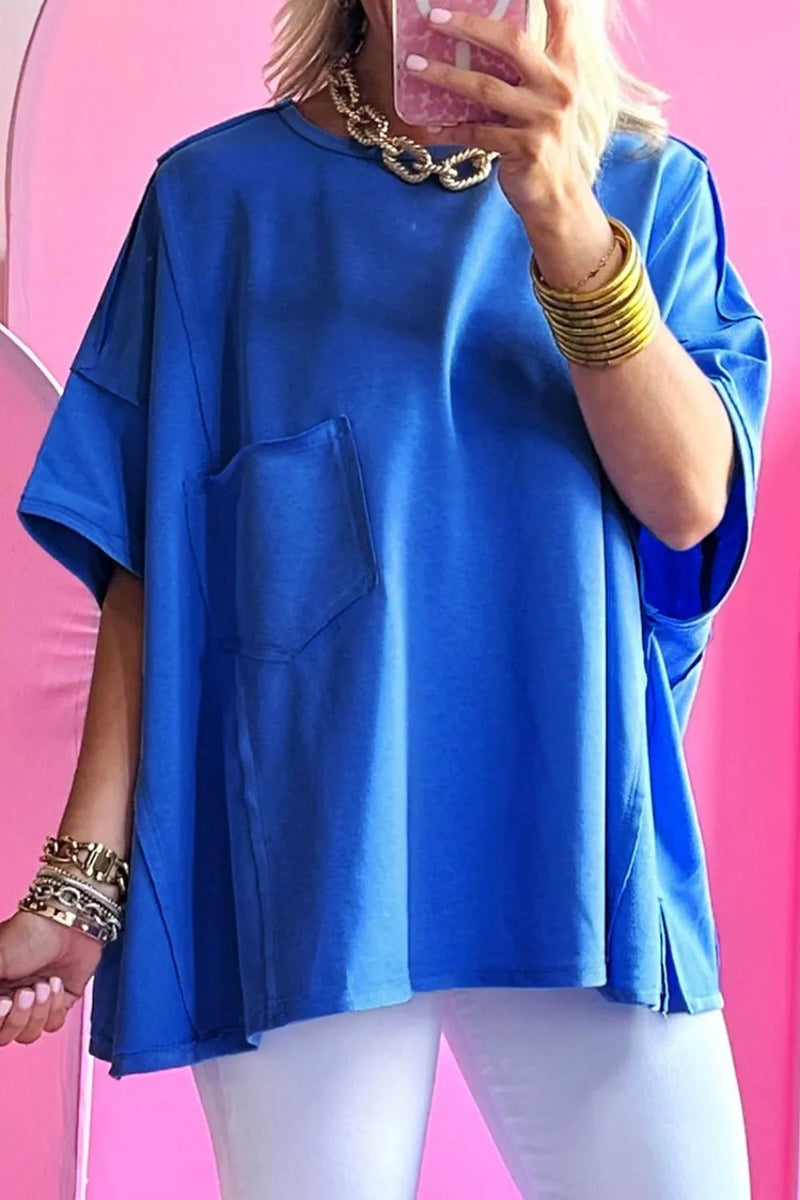 Person wearing a blue oversized shirt with dropped shoulders and one front pocket and raised seams