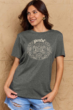 Grey tshirt with round neck and short sleeves, design is all in pink with Gemini above two long haired twins facing away from each other and encircled by a wreath of flowers and leaves.At the bottom of the design is a circle with Roman numeral Two in it.