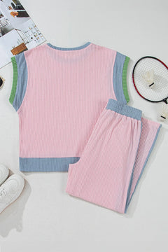 Pink ribbed short sleeved top and pants set on a white surface with a magazine and remote control in the background.