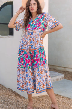 A colorful floral dress with tiers in different blocks of color patterns. Hem of skirt and sleeves in matching pattern for the trim, yoke and thigh area another block and the rest of dress in a third design. 