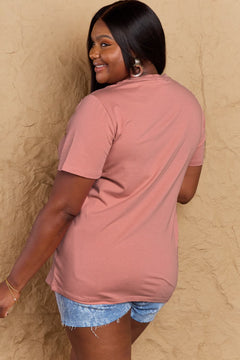 Woman wearing a pink t-shirt and denim shorts against a beige wall