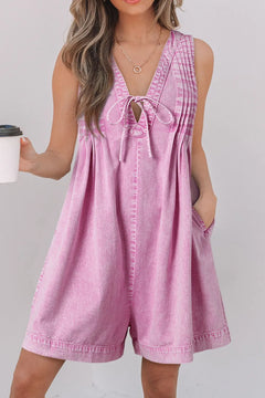 Faded Pink sleeveless denim romper with side pocket and deep v neck with denim bow tied across the lower part of the V.