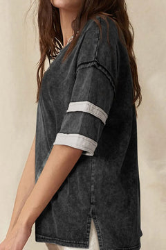 Person wearing a black distressed denim shirt with white trim on a beige background