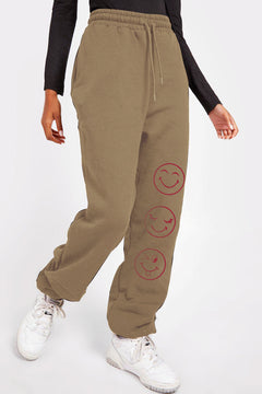 brown sweat pants with smiley face emojis down one leg