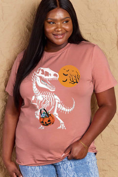Person wearing a pink t-shirt with a dinosaur skeleton and pumpkin design against a beige background