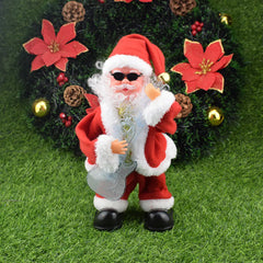 Decorative Santa Claus figure with sunglasses holding a guitar, standing on grass with a Christmas tree in the background.