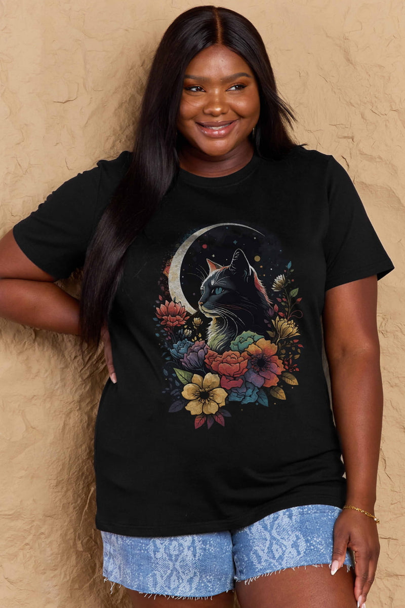 Black tshirt with short sleeves, round neck and styized design of long haired cat with blue eyes surrounded by blooming flowers with the glow of a sliver moon in the background