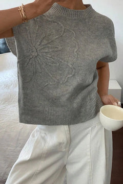 Gray sleeveless knitted top with floral pattern embroidered in same yarn on right front. Wide band hem matches neck and sleeves