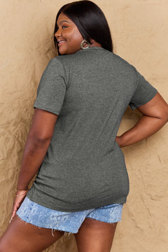 Woman wearing a gray t-shirt and denim shorts against a beige wall