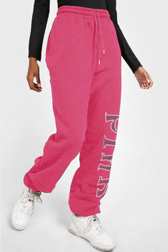 Pink drawstring sweat pants with pockets and the word PINK going down the left leg from knee to ankle in brownish letters outlined in white.