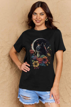Black tshirt with short sleeves, round neck and styized design of long haired cat with blue eyes surrounded by blooming flowers with the glow of a sliver moon in the background