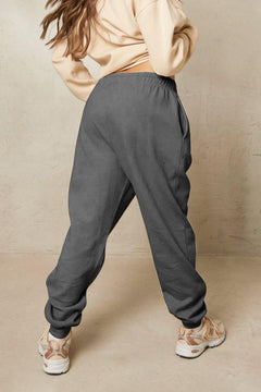 Person wearing gray sweatpants and a beige top against a beige background