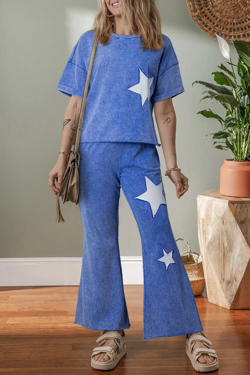 Woman wearing a blue outfit with star patterns on left side of top and down left leg.