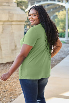 Woman wearing a green shirt and blue jeans standing outdoors.