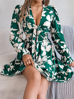 Woman wearing a green floral dress sitting on a couch.