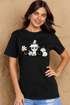 Woman wearing a black t-shirt with Halloween-themed design against a beige wall.