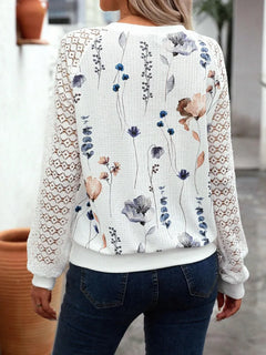 Person wearing a white floral-patterned sweater with lace sleeves.