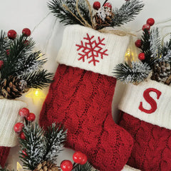 Red Christmas stockings style crew socks with snowflake and 'S' design, surrounded by festive decorations.