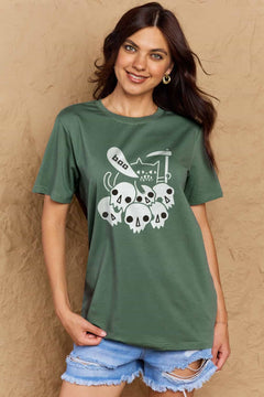 Green tshirt round neck with short sleeves and Halloween design of 6 white skulls below and outline of a cat saying boo and holding a scythe.