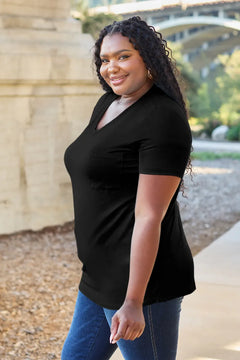 Woman wearing a black t-shirt and blue jeans standing outdoors with a bridge in the background