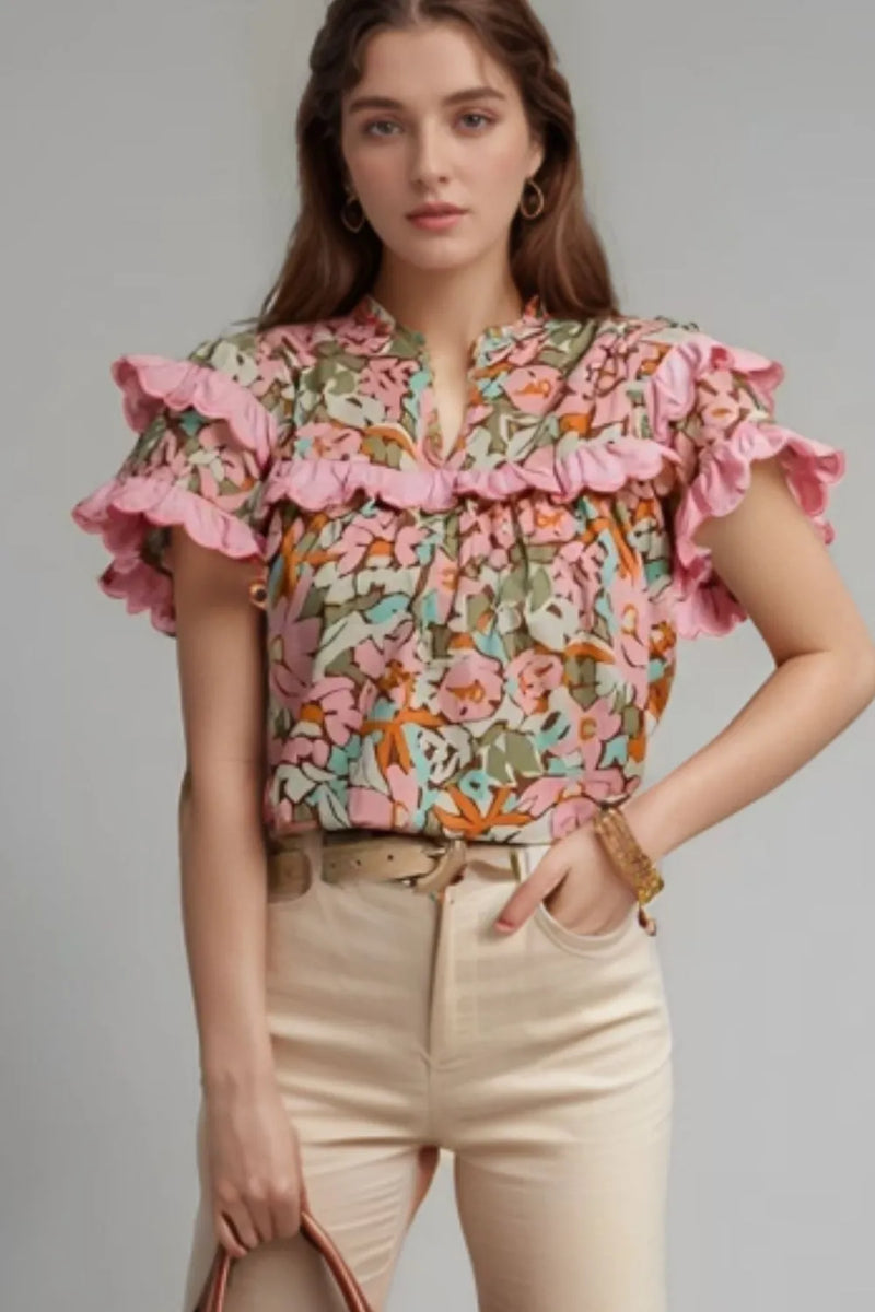 Floral blouse with short, ruffled sleeves and matching ruffle across the chest. Notched neck, no collar, green, blue, pink, orange, cream and brown colors.