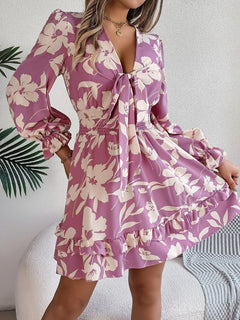 Woman wearing a purple floral dress with long sleeves against a neutral background