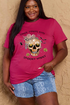 Pink t-shirt with a skull surrounded by small Jackolanterns, batts, flowers and a spider. The text Reads Thick Thighs and Spooky Vibes