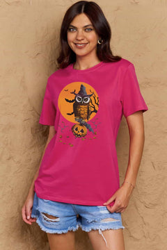 Woman wearing a pink t-shirt with a Halloween-themed graphic against a beige wall.