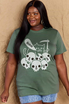Green tshirt round neck with short sleeves and Halloween design of 6 white skulls below and outline of a cat saying boo and holding a scythe.