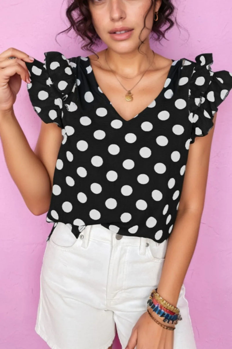 V necked black blouse with large white polka dots and short, ruffled sleeves.