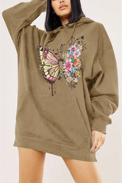 Person wearing a khaki hoodie with a butterfly and floral design on a plain background. Dropped shoulder and hand warmer pocket on front