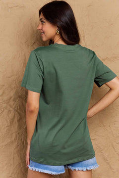Woman wearing a green t-shirt against a beige wall