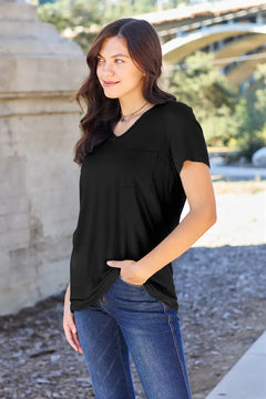 Woman wearing a black top and blue jeans standing outdoors with a blurred background