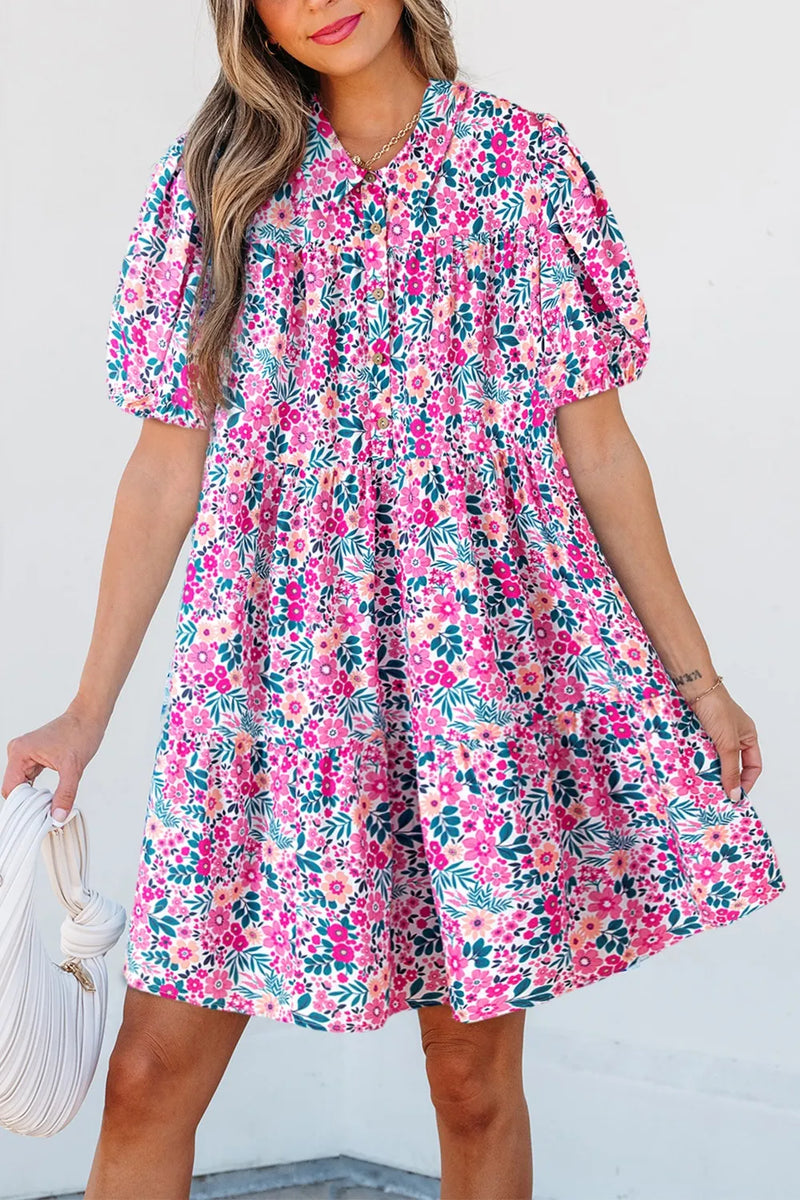 Loose floral patterned white dress with many, many different shades of pink flowers, as well as orange and creamy ones, with green foliage. Short sleeves with elastic hem. Collar and buttons up front.